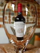 [Wine bottle seen through
 a large glass]